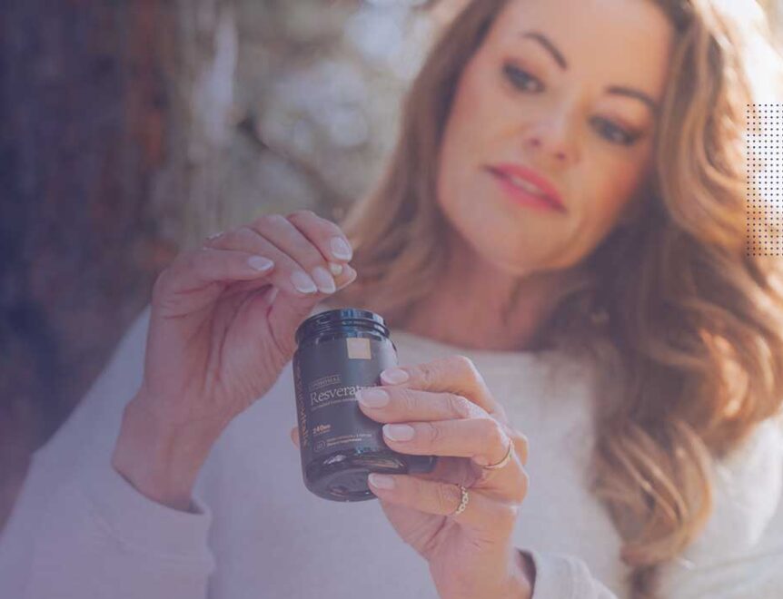O femeie care ține în mână un flacon cu capsule de resveratrol, evidențiind potențialul acestuia în îngrijirea pielii.
