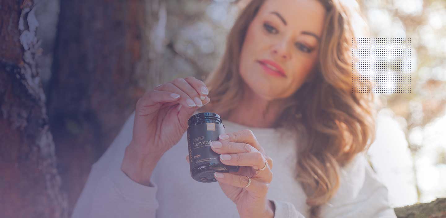 Een vrouw met een flesje resveratrolcapsules in haar hand, waarmee ze het potentieel ervan voor huidverzorging laat zien.