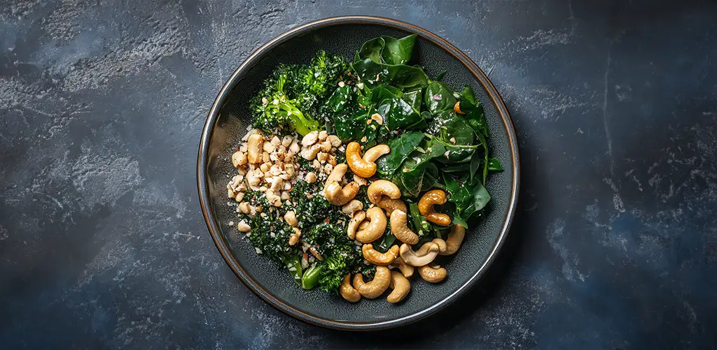 Verse bladgroenten en cashewnoten, beide uitstekende collageenrijke voedingsmiddelen voor vegetariërs, uitgestald op een rustieke houten tafel.