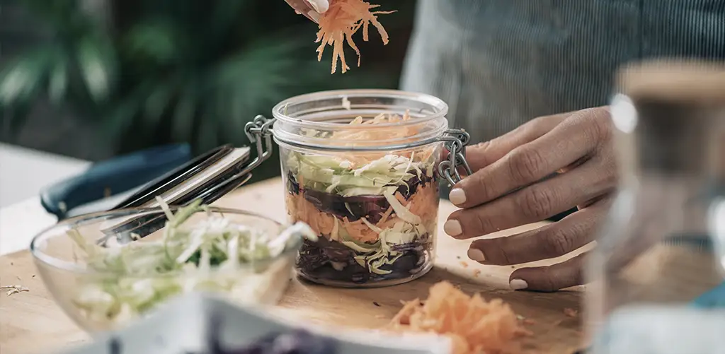 Een assortiment van probiotica-rijke voedingsmiddelen, waaronder yoghurt, kimchi, zuurkool en kombucha, uitgestald op een rustieke tafel. Deze voedingsmiddelen ondersteunen de darmgezondheid, wat volgens onderzoek een positieve invloed kan hebben op het verouderingsproces en een lang leven kan bevorderen door een evenwichtig darmmicrobioom te behouden. Ontdek hoe een gezonde darm kan bijdragen aan het algehele welzijn en een langer, gezonder leven kan ondersteunen.