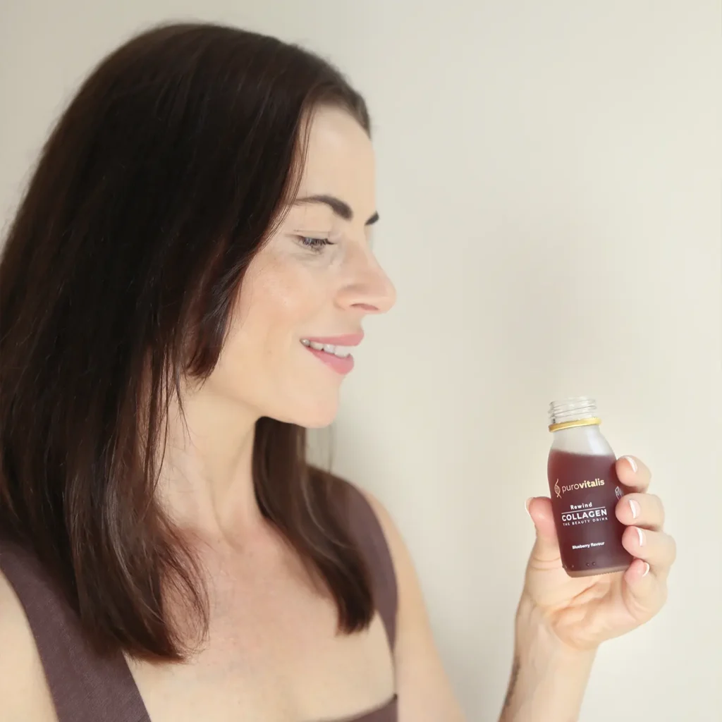 Bebida de colágeno líquido «Rewind» de Purovitalis, con L-ergoteoneína, antocianinas y otros ingredientes. En la foto aparece una mujer sosteniendo el suplemento «Beauty» de Purovitalis.
