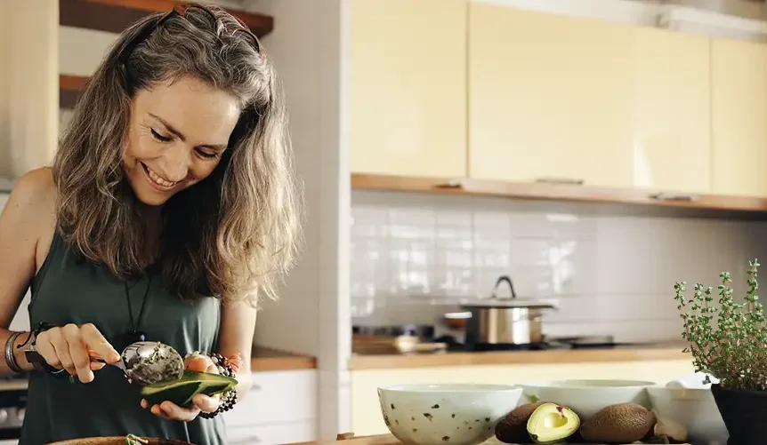 o femeie zâmbitoare în bucătărie, pregătind un avocado