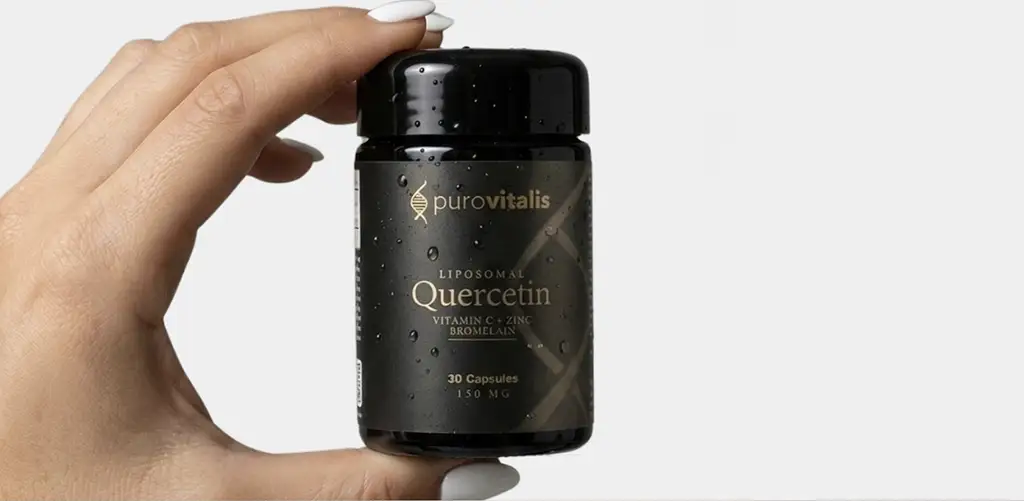 Hand die een vasthoudt black Flesje Purovitalis met opschrift "Liposomale quercetine met vitamine C, zink en bromelaïne", met daarop 30 capsules, tegen een lichte achtergrond.