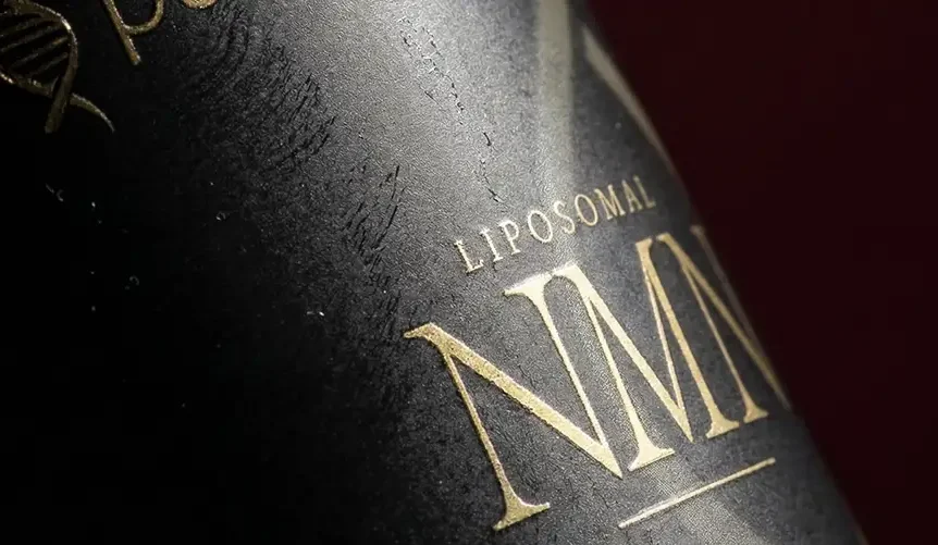Close-up of a black Purovitalis Liposomal NMN supplement bottle with gold lettering and a dark red background.