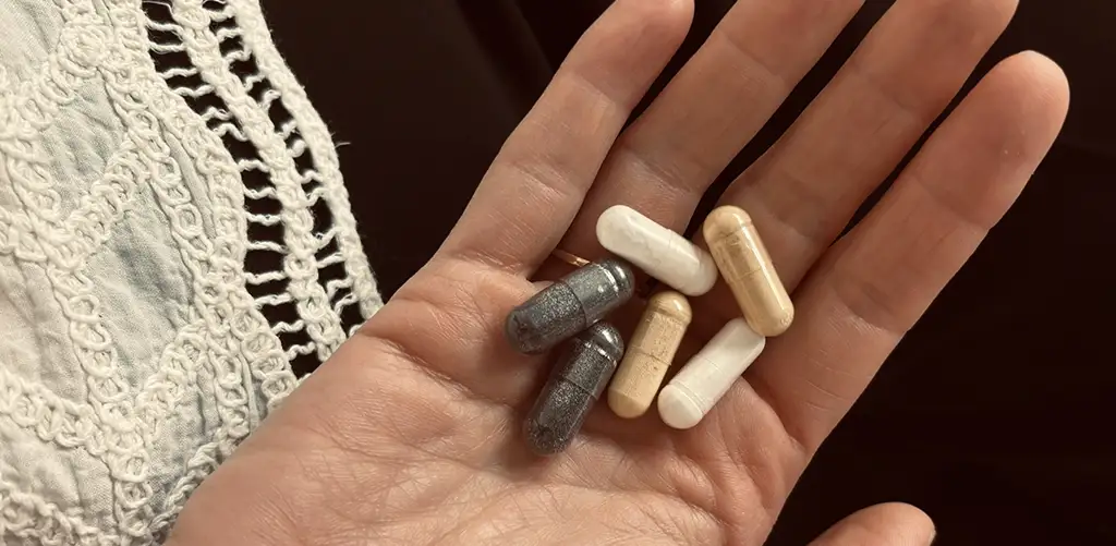 Hand holding a selection of longevity supplements in capsule form.