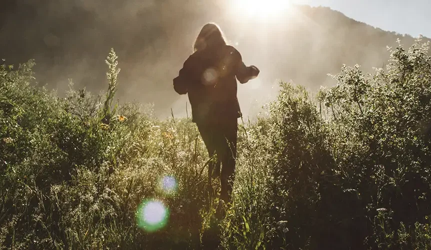 Woman in the morning light walking in the grass.
