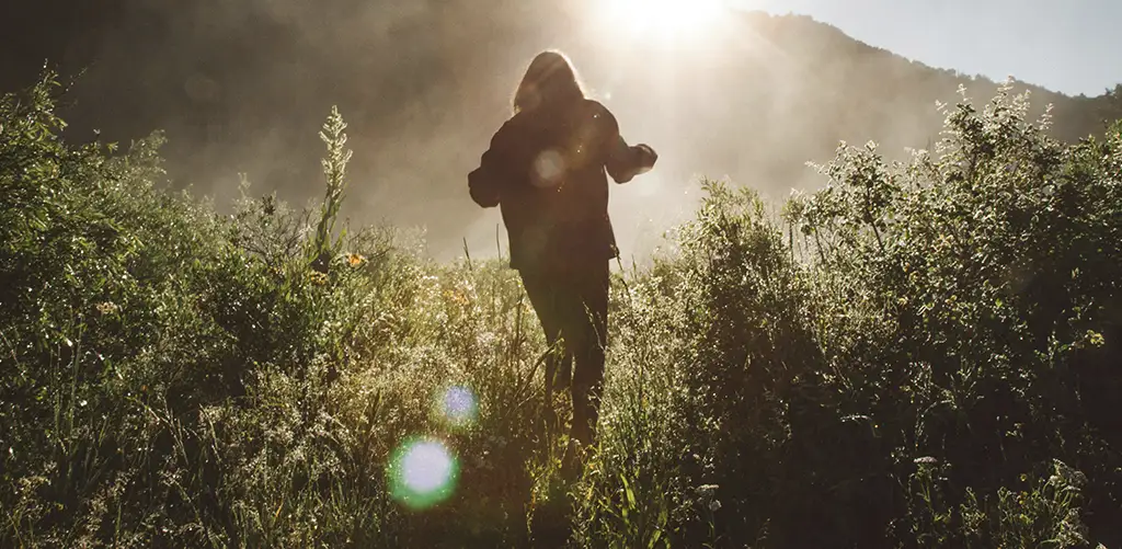 Woman in the morning light walking in the grass.